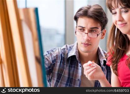 Artist coaching student in painting class in studio