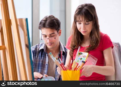 Artist coaching student in painting class in studio