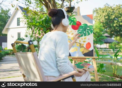 Artist concept, Female artist wear headphone to listening the music and painting picture on canvas.