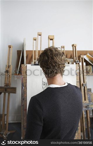 Artist drawing charcoal portrait in studio, back view