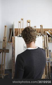 Artist drawing charcoal portrait in studio, back view