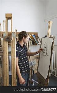 Artist drawing charcoal portrait in studio, side view
