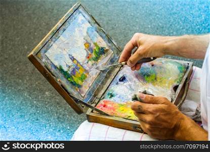 Artist drawing oil painting on a wooden canvas
