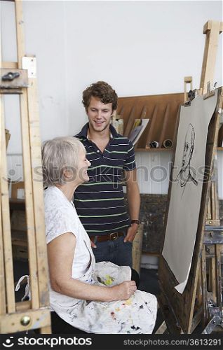 Artist drawing portrait in studio, young man looking on