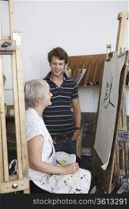 Artist drawing portrait in studio, young man looking on