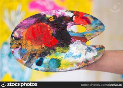 Artist holding colorful color palette. Painting therapy.