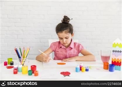 artist kid painting white paper desk against white brick wall