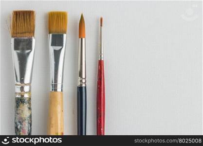 Artist paint brushes on canvas background. Top view with copy space.