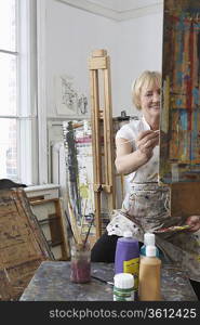 Artist painting at easel in studio