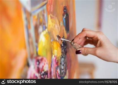 artist paints a picture of oil paint with palette-knife closeup
