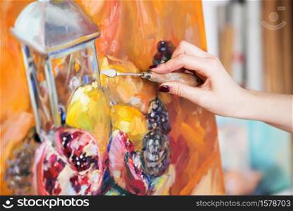 artist paints a still life picture of oil paint with palette-knife closeup