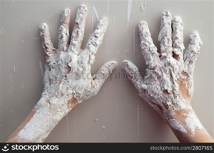 Artist plastering man hands with white dried cracked plaster texture in fingers