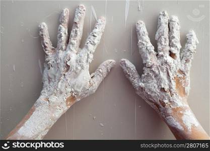 Artist plastering man hands with white dried cracked plaster texture in fingers
