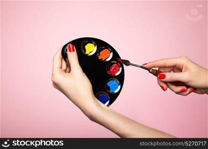 Artist&rsquo;s palette close-up. A palette of colors for painting makeup. Hand with manicure. Spatula artist