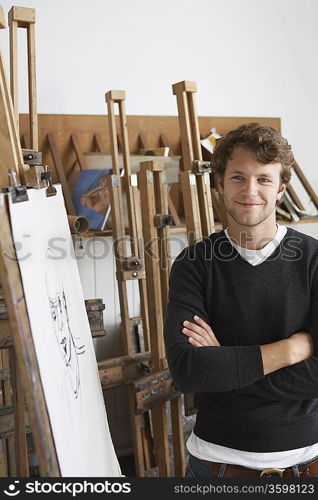 Artist standing by charcoal portrait in studio, smiling