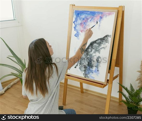artist woman painting canvas from shot