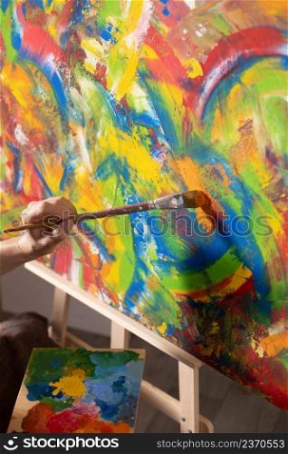Artist working on painting. Painter hand and brush in creative studio as art concept