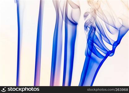 Artistic blue and yellow smoke of incence sticks isolated at white background. Artistic smoke of incence stick isolated at white background
