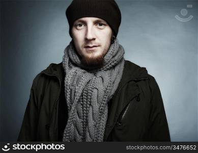 Artistic dark portrait of the young beautiful man in a cap and a dark jacket