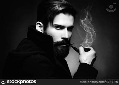 Artistic dark portrait of the young beautiful man. The young man smokes a tube. Close up. Black and white photo
