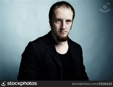 Artistic dark portrait of the young beautiful man with dark eyes. Shooting in studio