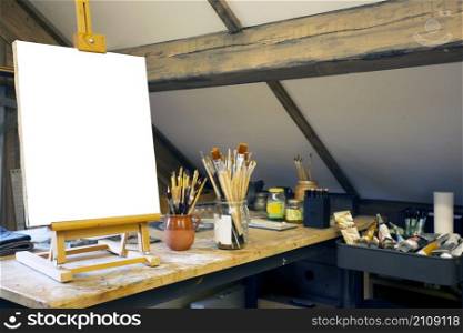 Artistic equipment in a artist studio: empty artist canvas on wooden easel and paint brushes Retro toned photo copy space space for text. Artistic equipment in a artist studio: empty artist canvas on wooden easel and paint brushes Retro toned photo copy space