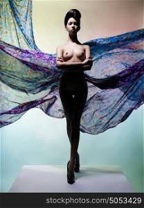Artistic fashion studio photo of nude elegant woman surrounded by flowing draperies. Perfect body. Beauty and health