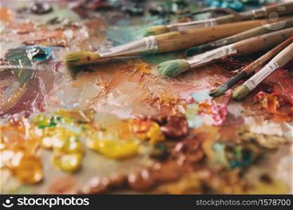 artists brushes and oil paints on wooden palette. Artist paintbrushes over palette with oil colors. palette with paintbrush and palette-knife