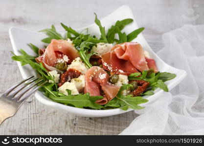 Arugula salad, prosciutto with sun-dried tomatoes, slices of mozzarella, capers, seasoned with olive butter and parmesan. A dish for those who monitor their health