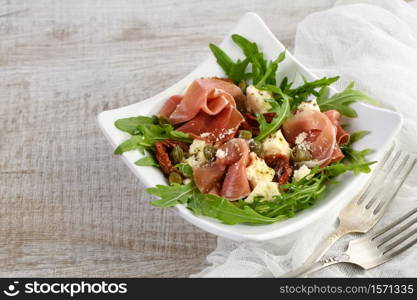 Arugula salad, prosciutto with sun-dried tomatoes, slices of mozzarella, capers, seasoned with olive butter and parmesan. A dish for those who monitor their health