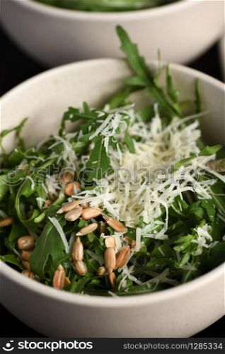 Arugula salad with sunflower kernels and sprinkled with grated parmesan