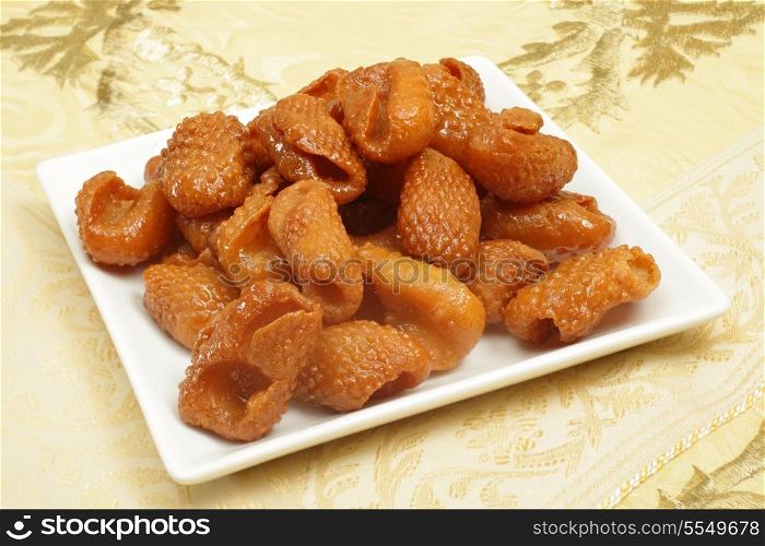 Asabe zeinab or Zeinabs fingers on a plate. This Middle Eastern sweet treat made of a semolina yeast dough, formed into this shape and coated in syrup. It is particularly popular in Ramadan.