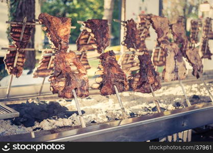 Asado, traditional barbecue dish in Argentina, roasted meat of beef cooked on a vertical grills placed around fire. Vintage look