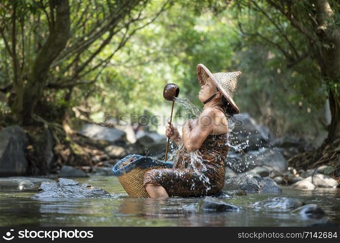Asaia old lady shower on river stream nature in countryside of living life senior woman farmer rural people / Natural Spa