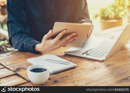 Asia business man using tablet and laptop on table in coffee shop with vintage toned filter.