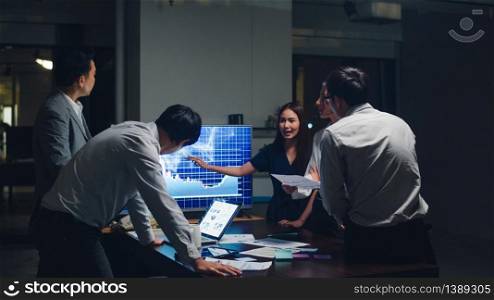 Asia businessmen and businesswomen meeting brainstorming ideas conducting business presentation project colleagues working together plan success strategy enjoy teamwork in small modern night office.