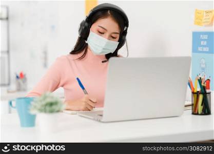Asia businesswoman social distancing in new normal situation for virus prevention while using laptop presentation to colleagues about plan in video call while work in office. Life after corona virus.