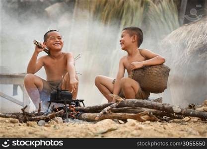 Asia child laugh / The boy friend happy funny laughing and smile at bonfire side with old kettle camping and hold fishing tools in the countryside of living life kids rural people