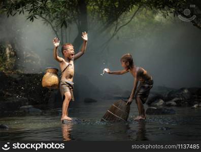 Asia child life laugh fisherman on river stream / The boy friend happy funny laughing and smile boy Fishing fish in hand at countryside of living life kids rural people