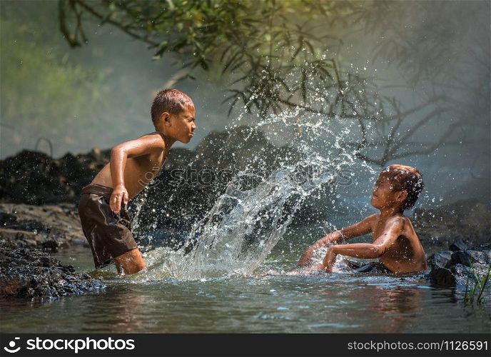 Asia children on river / The boy friend happy funny playing water in the water stream in countryside of living life kids farmer rural people