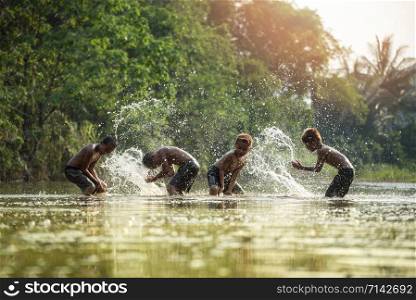 Asia children on river / The boy friend happy funny playing water in the water stream in countryside of living life kids farmer rural people