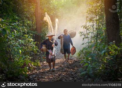 Asia fisherman hold net and fishing tools walking in the forest to river life person countryside