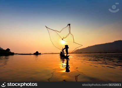 Asia fisherman net using on wooden boat casting net sunset or sunrise in the Mekong river - Silhouette fisherman boat with mountain background life person countryside