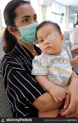 Asia Infant is strabismus and Have eyes closed for physical in treatment,and have Mother is holding.