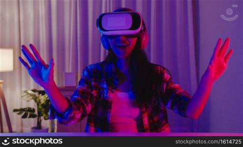Asia lady wear VR game headset having fun experience wearable virtual augmented ar reality digital innovation technology happy moment New Year neon night party event celebration in living room at home