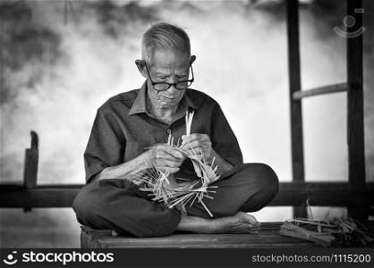 Asia life old man uncle grandfather working in home / Man elderly serious living in the countryside of life rural people in thailand weave bamboo basket crafts