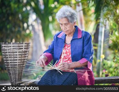 Asia life old woman working in home / Grandmother serious living in the countryside of life rural people in thailand weave bamboo basket crafts