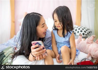 Asia mother and daughter enjoy playing smartphone