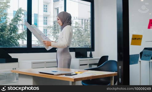 Asia muslim lady drawing work plan think information reminder on paper in new normal office. Working from home, remotely work, self isolation, social distancing, quarantine for coronavirus prevention.
