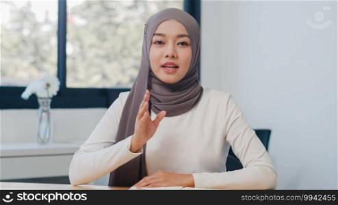 Asia muslim lady looking at camera talk to colleagues about plan in video call in new normal office. Working from home, remotely work, self isolation, social distancing, quarantine for coronavirus.